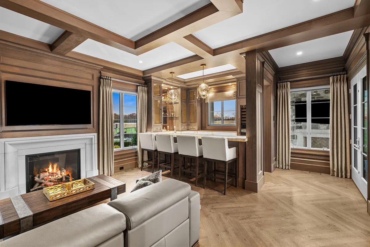 Oak-panelled family room with a coffered ceiling, lit fireplace and bar seating