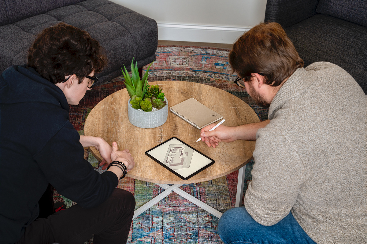 Creative team planning a product shoot around a tablet and sketchbook in the studio